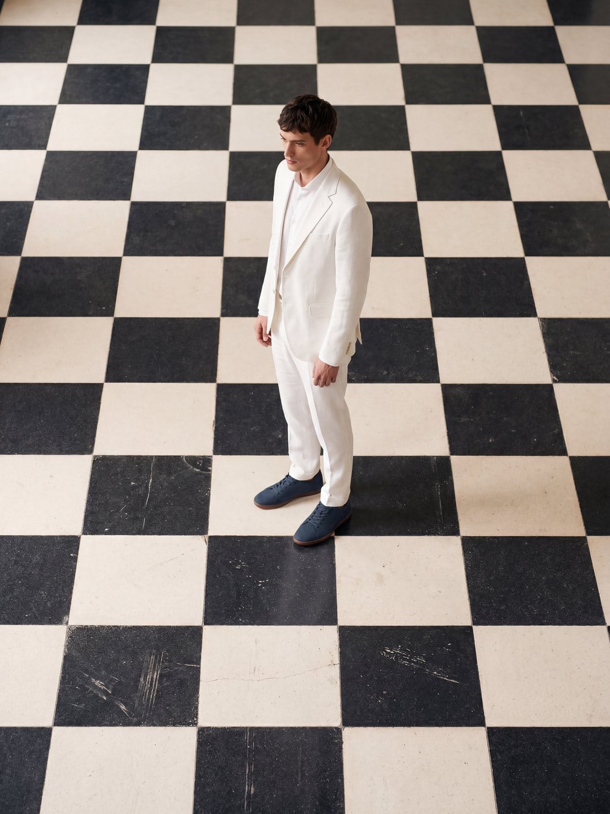 Man in a white suit on a black-and-white checkerboard floor